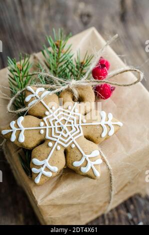 Cadeau de Noël décoré avec un biscuit au pain d'épice et une branche de ficelle verte sur fond de bois. Boîte cadeau en papier artisanal. Carte de vœux de saison. Banque D'Images