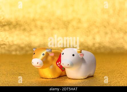 Carte de vœux avec un gros plan sur deux mignons faits main figurines de l'animal du zodiaque de deux vaches peintes à la main en or et blanc pour l'année du boeuf Banque D'Images
