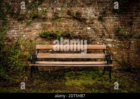 Banc en bois de style ancien et mur en brique rouge dans le stationnement Banque D'Images