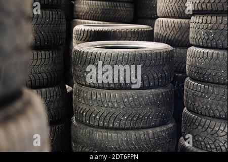 Pile de pneus à pointes et de semelles usagés dans un entrepôt de voitures. Pile de pneus anciens. Banque D'Images