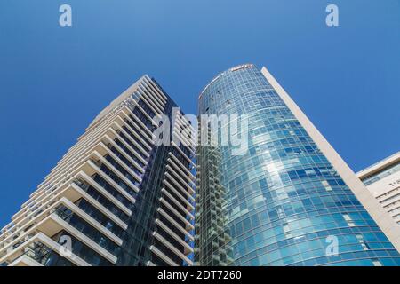 Lave-glaces suspendus à des cordes à l'extérieur d'une tour moderne en verre architectural incurvé et en acier, tel Aviv, Israël Banque D'Images