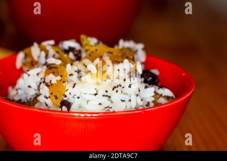 Préparation à la main de gâteries pour Noël orthodoxe traditionnelle - riz au lait avec des fruits, les canneberges, le miel, les noix, l'Église des bougies sur un onglet en bois Banque D'Images