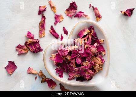 Pétales de rose séchés sur un cuillère en forme de coeur Banque D'Images