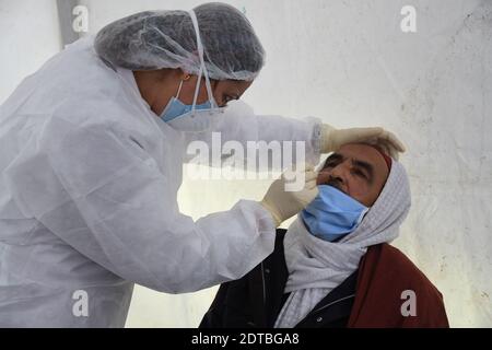 Tunis, Tunisie. 21 décembre 2020. Un travailleur médical prélève un échantillon d'écouvillon auprès d'un homme pour le test COVID-19 dans le centre-ville de Tunis, en Tunisie, le 21 décembre 2020. Le Gouvernement municipal de Tunis a procédé à des tests rapides et gratuits de la COVID-19 dans trois zones densément peuplées de la ville, du lundi au mercredi. Crédit: Adel Ezzine/Xinhua/Alamy Live News Banque D'Images