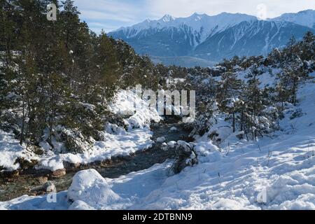 Paysage d'hiver ensoleillé dans la neige profonde avec ruisseau de montagne et forêt de pins dans les Alpes autrichiennes, Mieming, Tyrol, Autriche Banque D'Images
