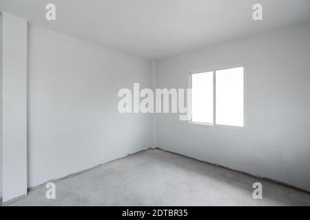 Sol en ciment de béton avec mur blanc et fenêtre. En construction, l'intérieur de la chambre est vide Banque D'Images