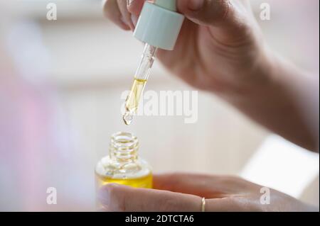 Mains de femme tenant une bouteille d'huile de CDB et un compte-gouttes Banque D'Images