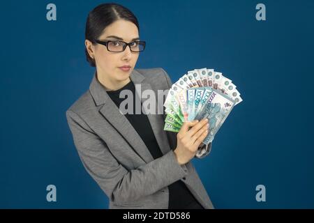 Jeune belle femme en lunettes montrant un paquet de tenge kazakhe et des roubles russes dans sa main. Mise au point sélective. Banque D'Images