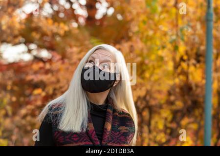 Portrait d'une femme âgée portant un masque de protection Covid à l'extérieur automne Banque D'Images