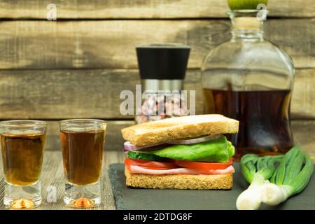 Un sandwich et un verre de vodka maison. Sandwich et whisky maison pour une bouchée rapide. Arrière-plan du texte Banque D'Images