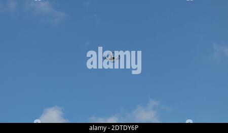 Drone en vol au-dessus des couronnes d'arbres. Photo d'un drone volant sur fond de ciel bleu et de nuages blancs. Le drone regarde Banque D'Images