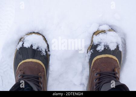 Vue de dessus du voyageur anonyme en bottes chaudes debout sur la neige blanche le jour d'hiver. Banque D'Images