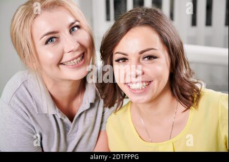 Portrait de deux jeunes belles femmes, dentiste avec sa patiente, assise dans un cabinet dentaire, souriant à la caméra, montrant des bretelles sur leurs dents. Concept de traitement orthodontique, dentisterie Banque D'Images