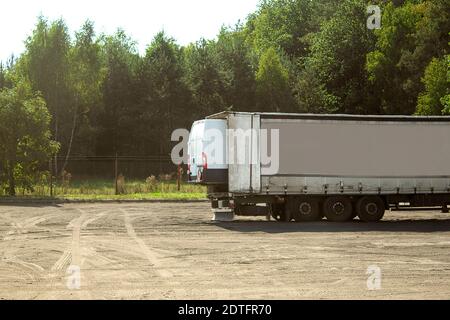 Voiture dans une remorque de camion. Un gros camion transporte une petite voiture dans une remorque Banque D'Images
