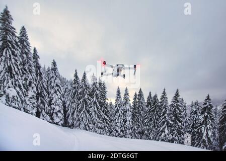 Drone vient de se lever en vol après une chute de neige près des arbres Banque D'Images