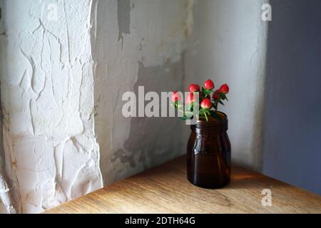 Fleur artificielle rouge dans un pot en verre décoré sur une table en bois- Décoration intérieure Banque D'Images