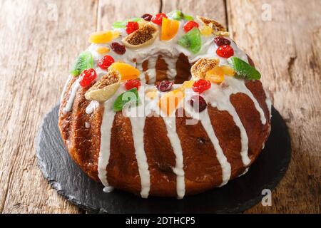 Gâteau de fête aux raisins secs, abricots séchés, cerises séchées, kiwis et canneberges et glaçage en gros plan sur une planche sur la table. Horizontal Banque D'Images