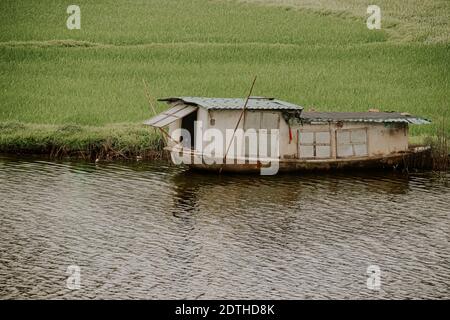 Décor cinématographique d'une maison de bateau en bois amarrée au bord de la rivière de Ninh Binh, Vietnam Banque D'Images