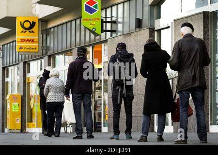 Dortmund, Allemagne, 18 décembre 2020: Les clients attendent sur le trottoir devant une succursale de Deutsche Post / DHL à Dortmund. En raison des restrictions du deuxième verrouillage de la pandémie de corona, seuls 3 clients sont autorisés à rester dans cette succursale en même temps. Banque D'Images