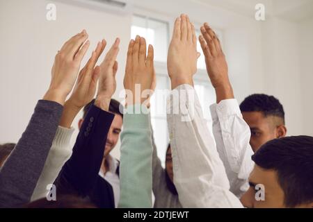 Une équipe de jeunes qui se soulèvent les mains dans les airs, votant pour la bonne idée ou faisant preuve de solidarité Banque D'Images