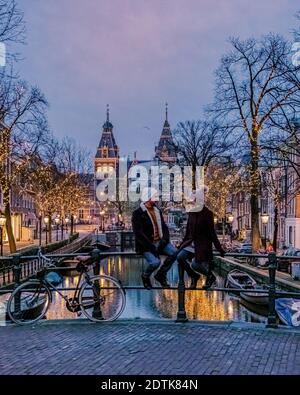 Couple en voyage à Amsterdam canaux des pays-Bas avec des lumières de Noël pendant décembre, canal centre historique d'Amsterdam la nuit. Europe Banque D'Images