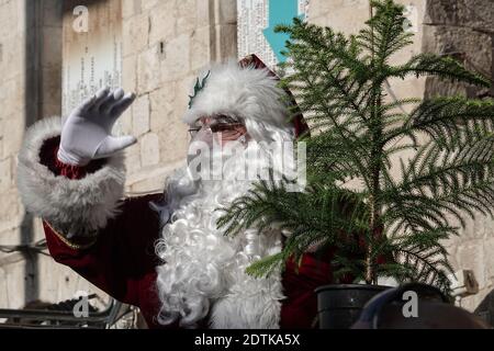 Jérusalem, Israël. 22 décembre 2020. Le Père Noël, ou « Baba Noel » comme il est appelé en arabe, se déplace à dos de chameau pour remplacer le renne près de la porte Jaffa de la vieille ville de Jérusalem. La municipalité de Jérusalem et le Fonds national juif ont distribué des cyprès d'Arizona spécialement cultivés à la population chrétienne à la porte de Jaffa. Crédit : NIR Amon/Alamy Live News Banque D'Images