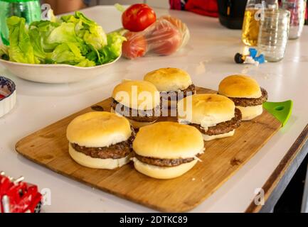 Une planche en bois avec mini hamburgers prêts à être servis Banque D'Images