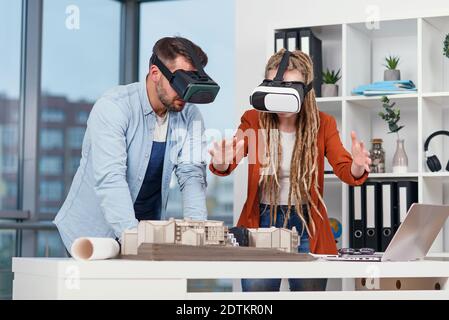 Architecte professionnel travaillant au bureau et le port d'un casque VR, il est l'affichage d'une interface de réalité virtuelle Banque D'Images