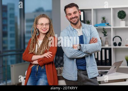 L'architecte professionnel se tient dos à dos avec une jolie femme collègue avec des dreadlocks dans le studio de design. Banque D'Images