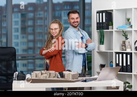 L'architecte professionnel se tient dos à dos avec une jolie femme collègue avec des dreadlocks dans le studio de design. Banque D'Images