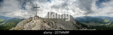 Un orage approchant baigne l'ouest du Karwendel avec le marché Mittenwald et les montagnes Wetterstein dans les Alpes bavaroises dans une ambiance sombre. La croix du sommet du Viererspitze se distingue clairement. Banque D'Images