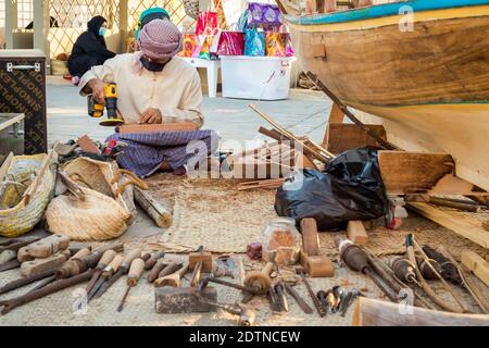 Pêcheur arabe, réparant filet de pêche maison et yacht en bois, portant un masque facial et s'assoit sur le sol du boam traditionnel Banque D'Images