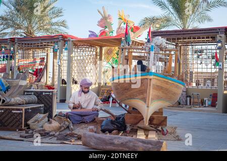 Pêcheur arabe, réparant filet de pêche maison et yacht en bois, portant un masque facial et s'assoit sur le sol du boam traditionnel Banque D'Images