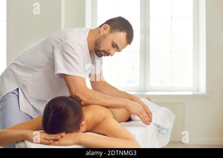 Massagiste professionnel effectuant un massage du dos pour une jeune femme allongé table de massage Banque D'Images