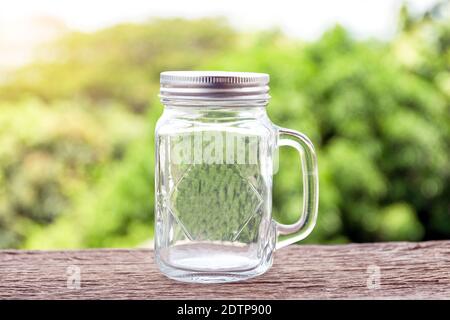 Un pot en verre avec poignée pour prendre un verre sur parquet avec fond vert nature. Banque D'Images