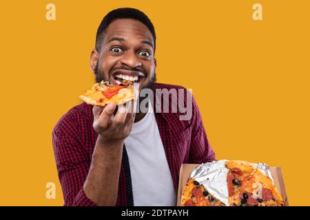 Portrait de drôle Black Guy manger Pizza posant dans le studio Banque D'Images