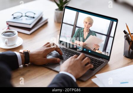 Homme d'affaires noir méconnaissable ayant un jeu vidéo avec un partenaire d'affaires, utilisant un ordinateur portable Banque D'Images