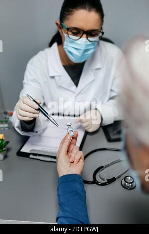 Femme médecin expliquant à son patient les avantages et les risques du vaccin contre le coronavirus Banque D'Images