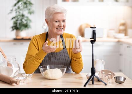 Femme âgée blogueuse de nourriture enregistrant sa cuisine par dans la cuisine Banque D'Images