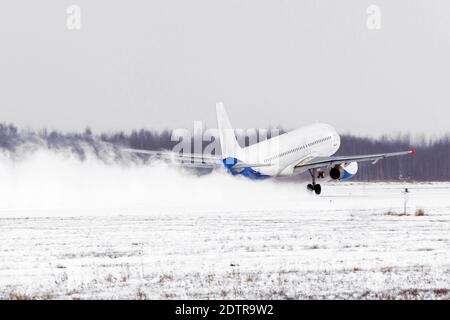 Décollage de l'avion de l'aéroport couvert de neige par mauvais temps pendant une tempête de neige, un vent fort en hiver Banque D'Images