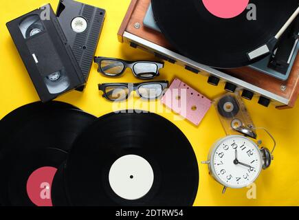 Attributs de style rétro Flat lay, supports 80. Lecteur de vinyle, cassettes vidéo, cassettes audio, disques, lunettes 3d, réveil vintage, vieux livres sur yel Banque D'Images