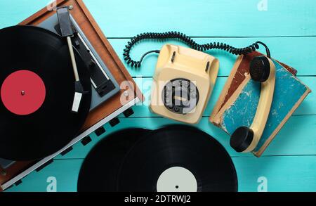 Lecteur de vinyle, téléphone rotatif, plaques de vinyle, livres anciens. Objets à l'ancienne sur fond de bois bleu. Style rétro, années 70. Vue de dessus. Banque D'Images