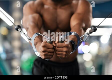 Triceps d'entraînement d'athlète noir non reconnaissable sur l'exercice croisé en salle de sport Banque D'Images