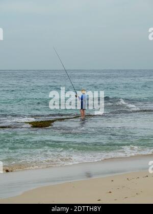 Homme pêche à la plage avec canne de pêche debout sur le récif à Guilderton Australie occidentale Banque D'Images