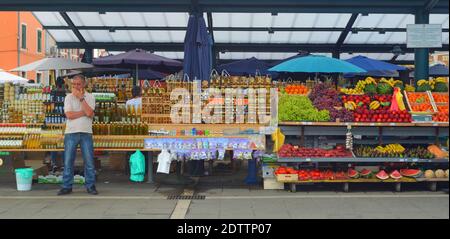 Négociant de marché debout devant les stands de pétrole, de Herb et de fruits sans clients. Banque D'Images