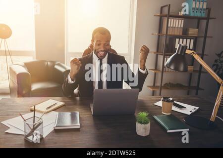 Portrait d'un homme afro-américain ravie assis bureau ordinateur portable de travail célébrez le partenariat atteindre le contrat soulever les poings crier oui porter tux combinaison tuxedo Banque D'Images