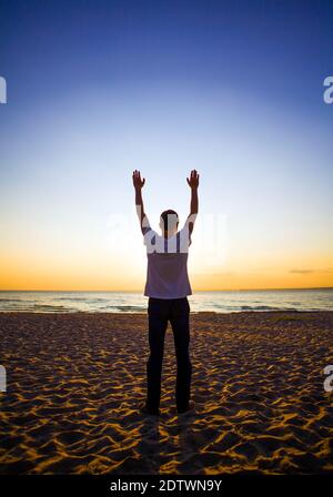 Homme Silhouette priant au coucher du soleil sur le fond de la mer Banque D'Images