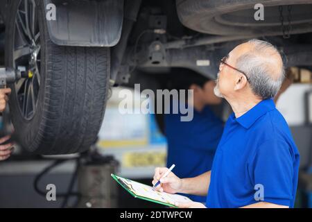Mécanicien examinant le dessous de la voiture de service, le service de réparation automobile. Banque D'Images