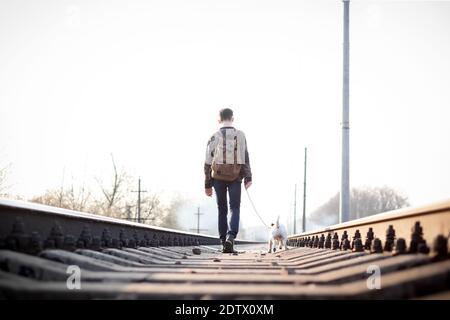 Adolescent sur marche ferroviaire avec petit chien blanc. La liberté et la solitude concept Banque D'Images