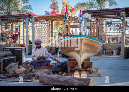 Pêcheur arabe, réparant filet de pêche maison et yacht en bois, portant un masque facial et s'assoit sur le sol du boam traditionnel Banque D'Images